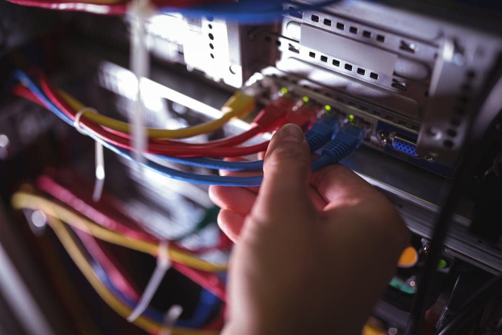 Close-Up of technician plugging patch cable in a rack mounted server in server room-1