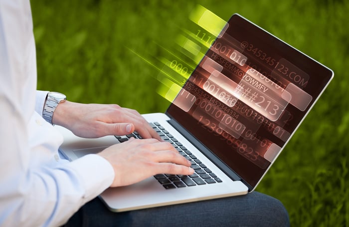 Close up of man typing on laptop computer with glowing technology effect