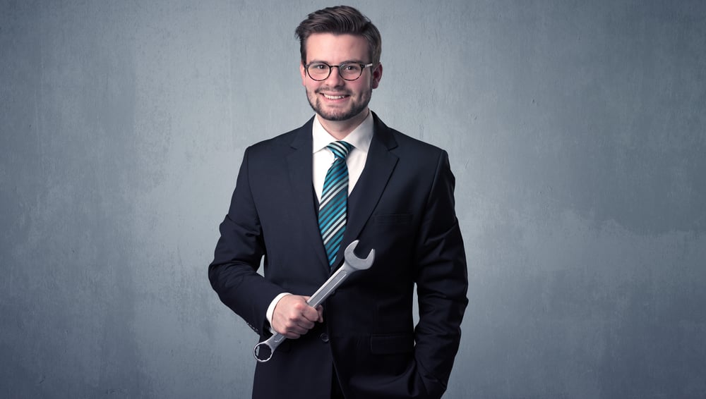 Young, handsome, cute businessman holding tool with grey background